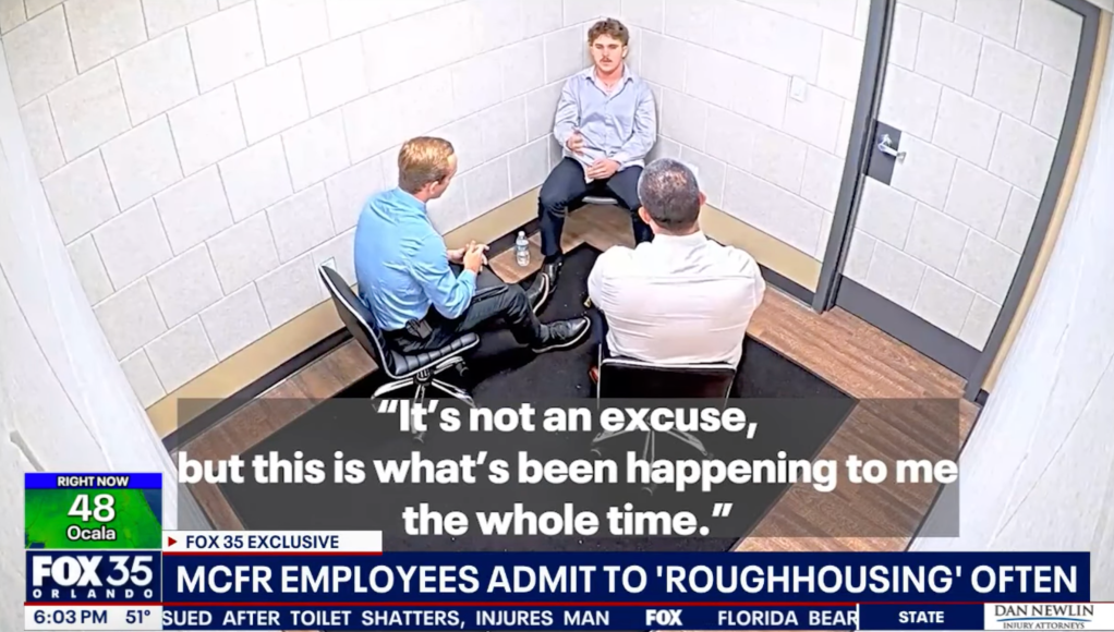 A young man being interviewed by two other men in a room.